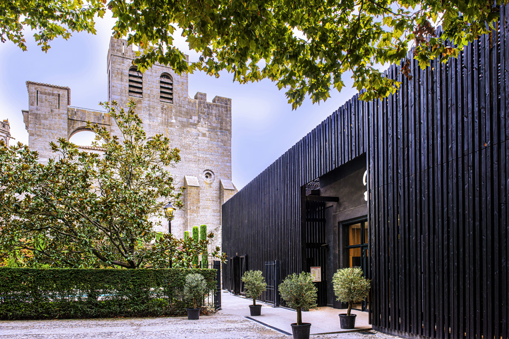 a building with a black wall and trees