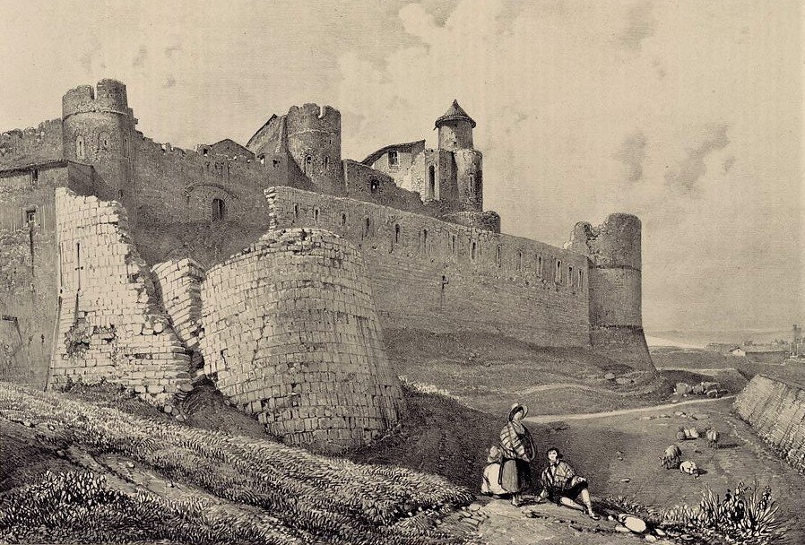 a stone castle with a man and woman sitting on a dirt road