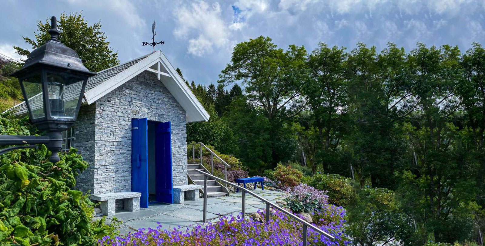 a stone building with a blue door and a bench in front of it