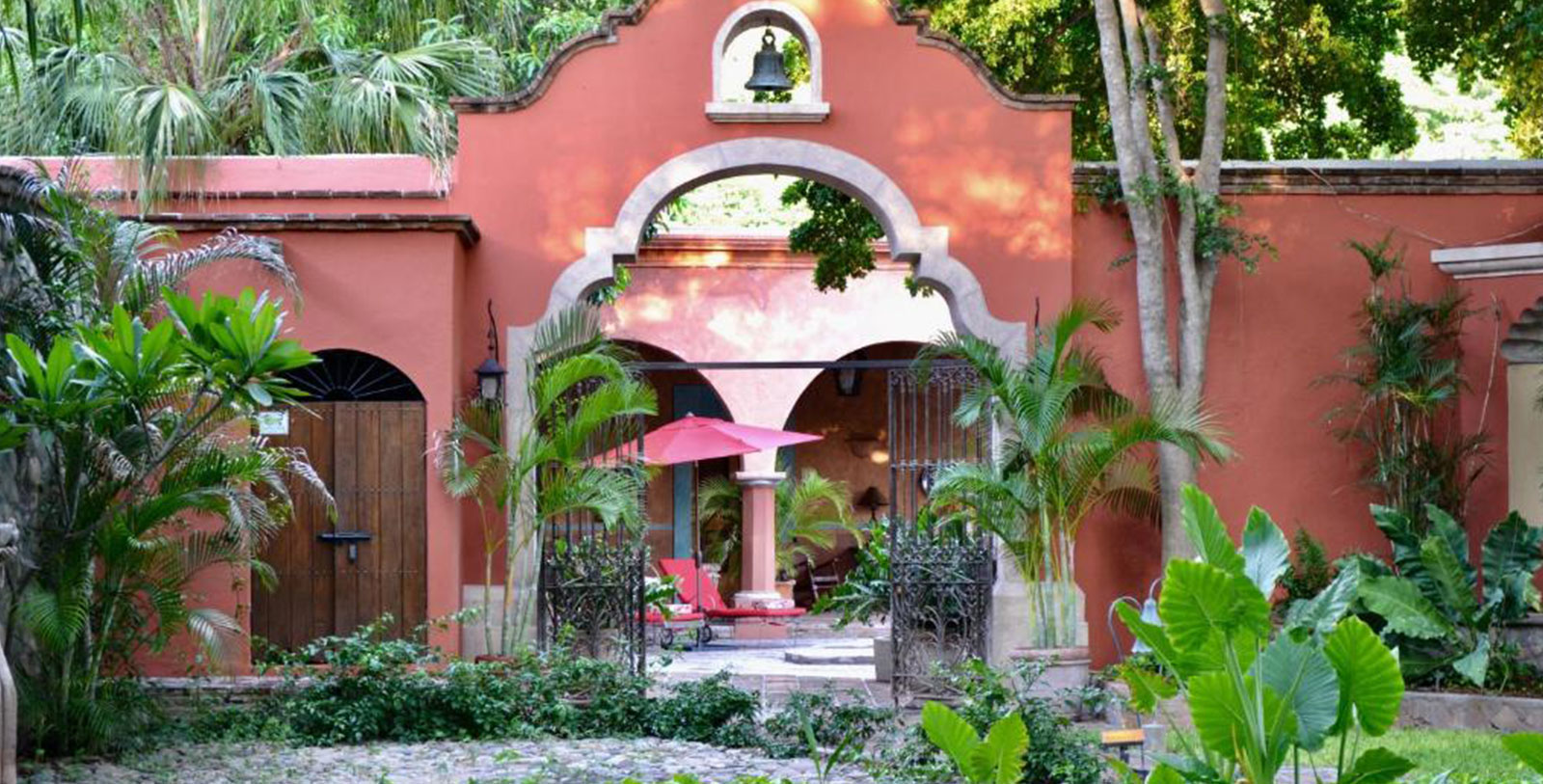a red building with a bell and a bell on the gate