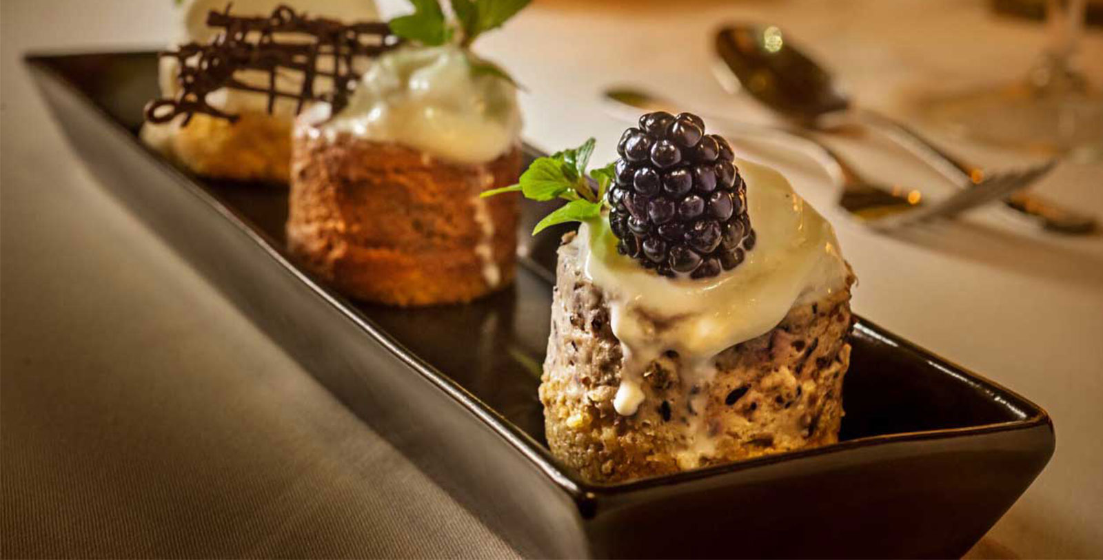 a plate of desserts with a blackberry on top