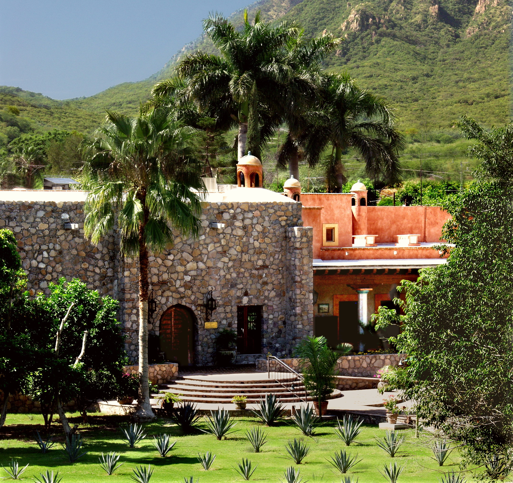 a building with a stone wall and palm trees