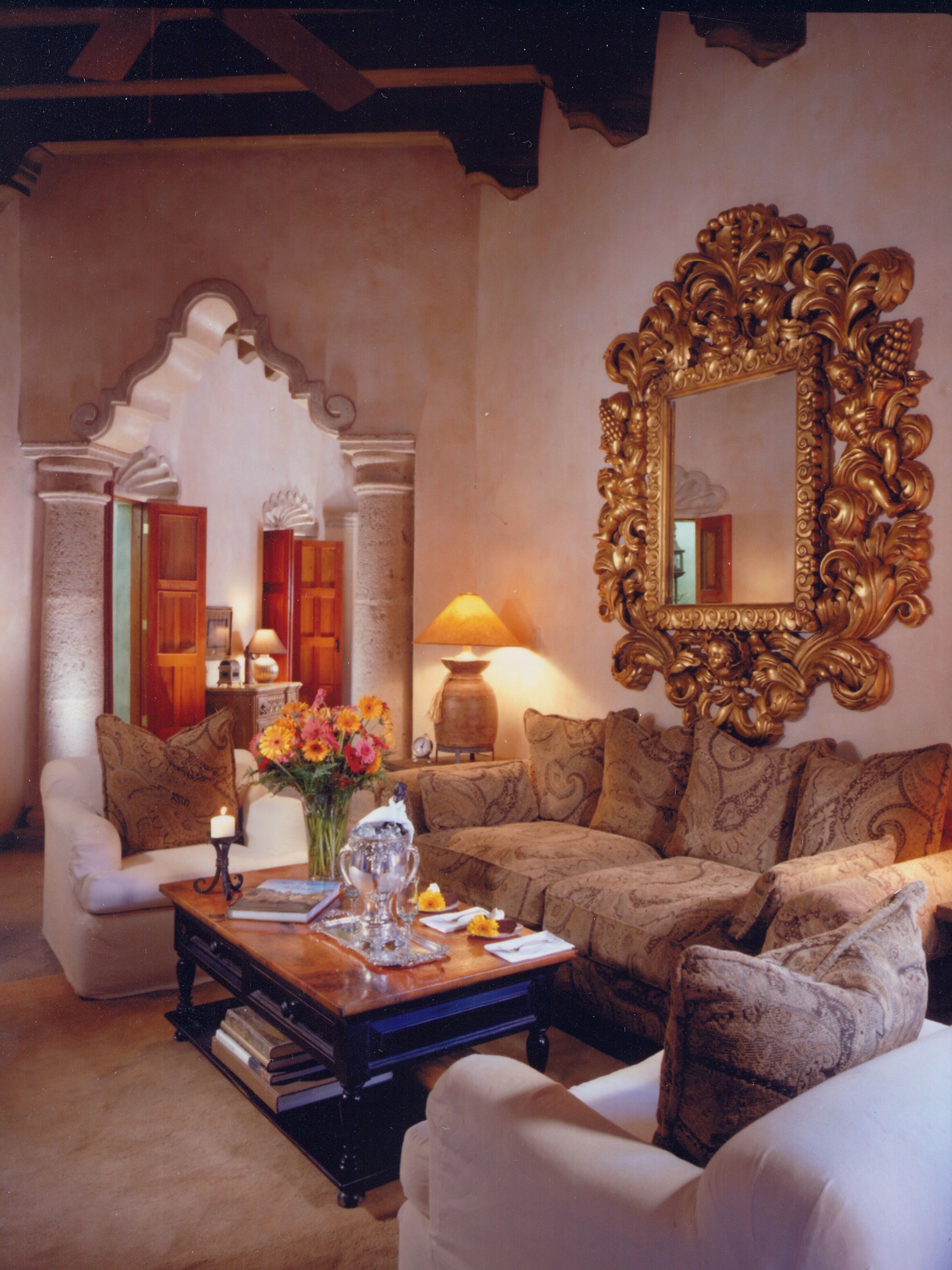 a living room with a gold mirror and couches