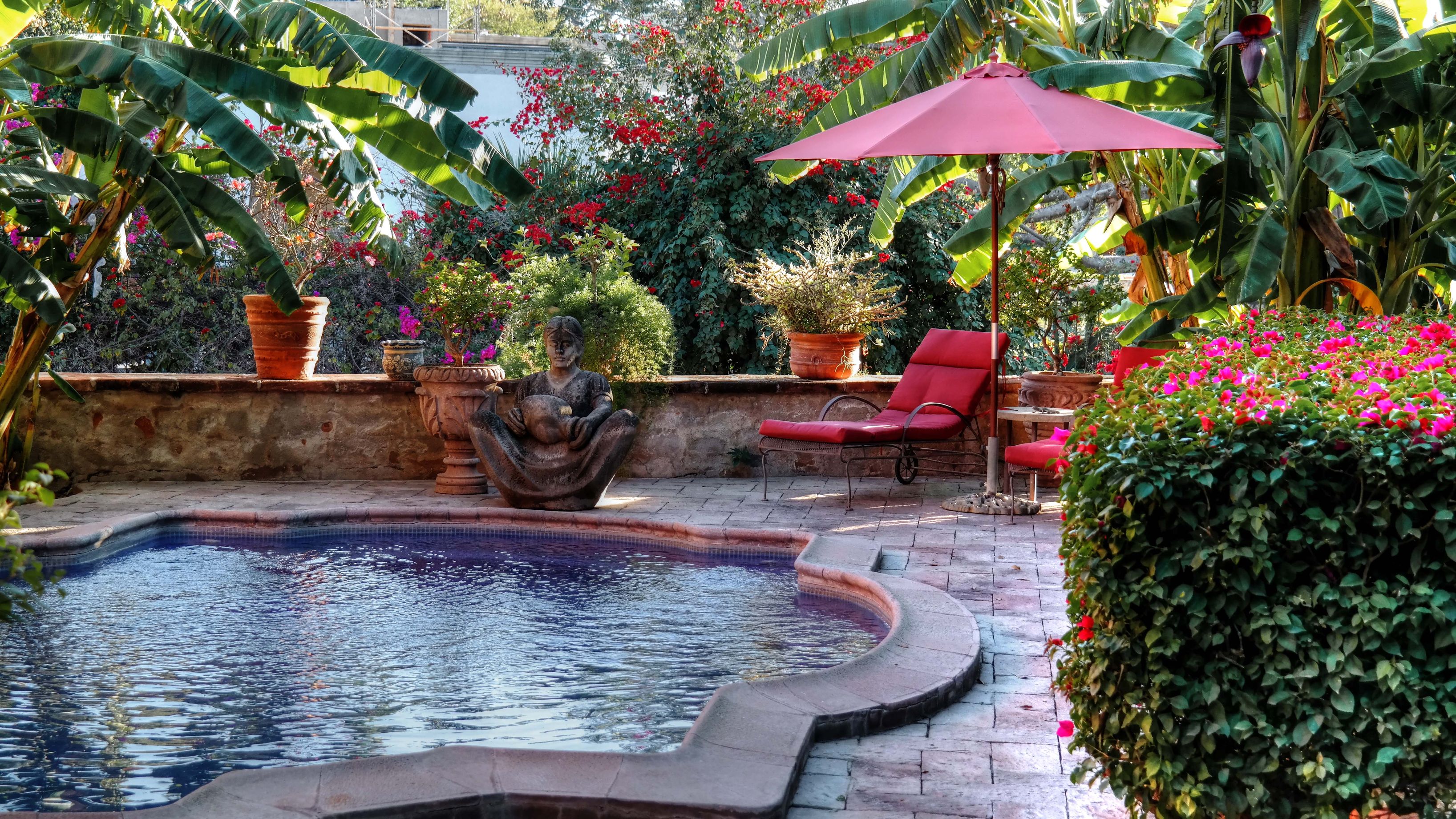 a pool with a statue and a red umbrella