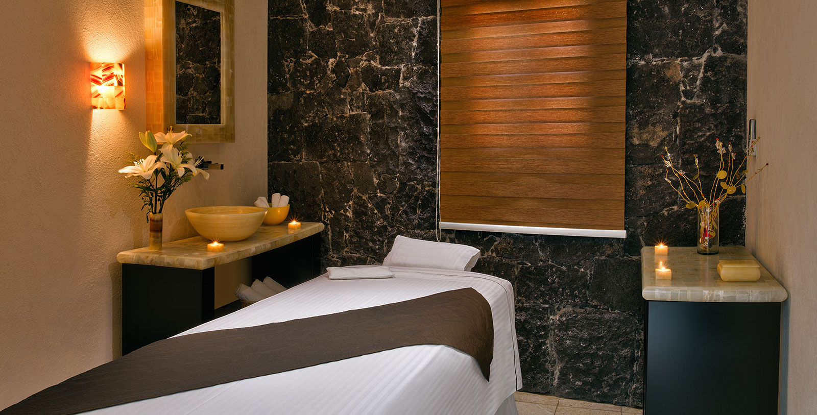 a massage room with a bed and bowls on the counter