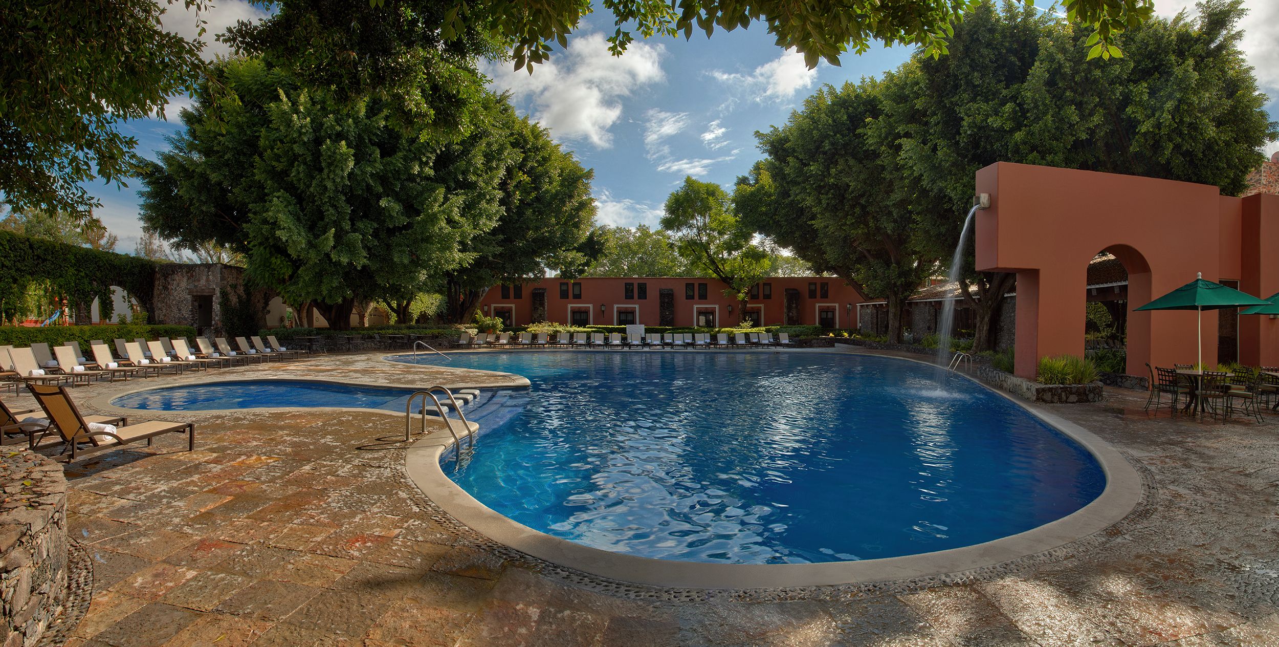 a pool with a fountain and trees