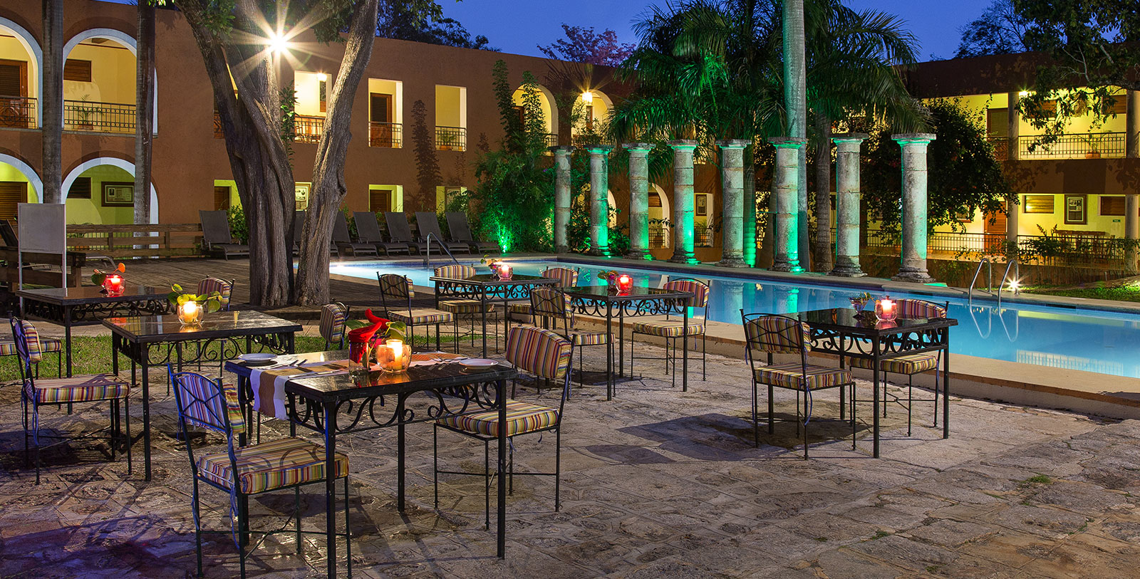 a pool with tables and chairs in front of a building