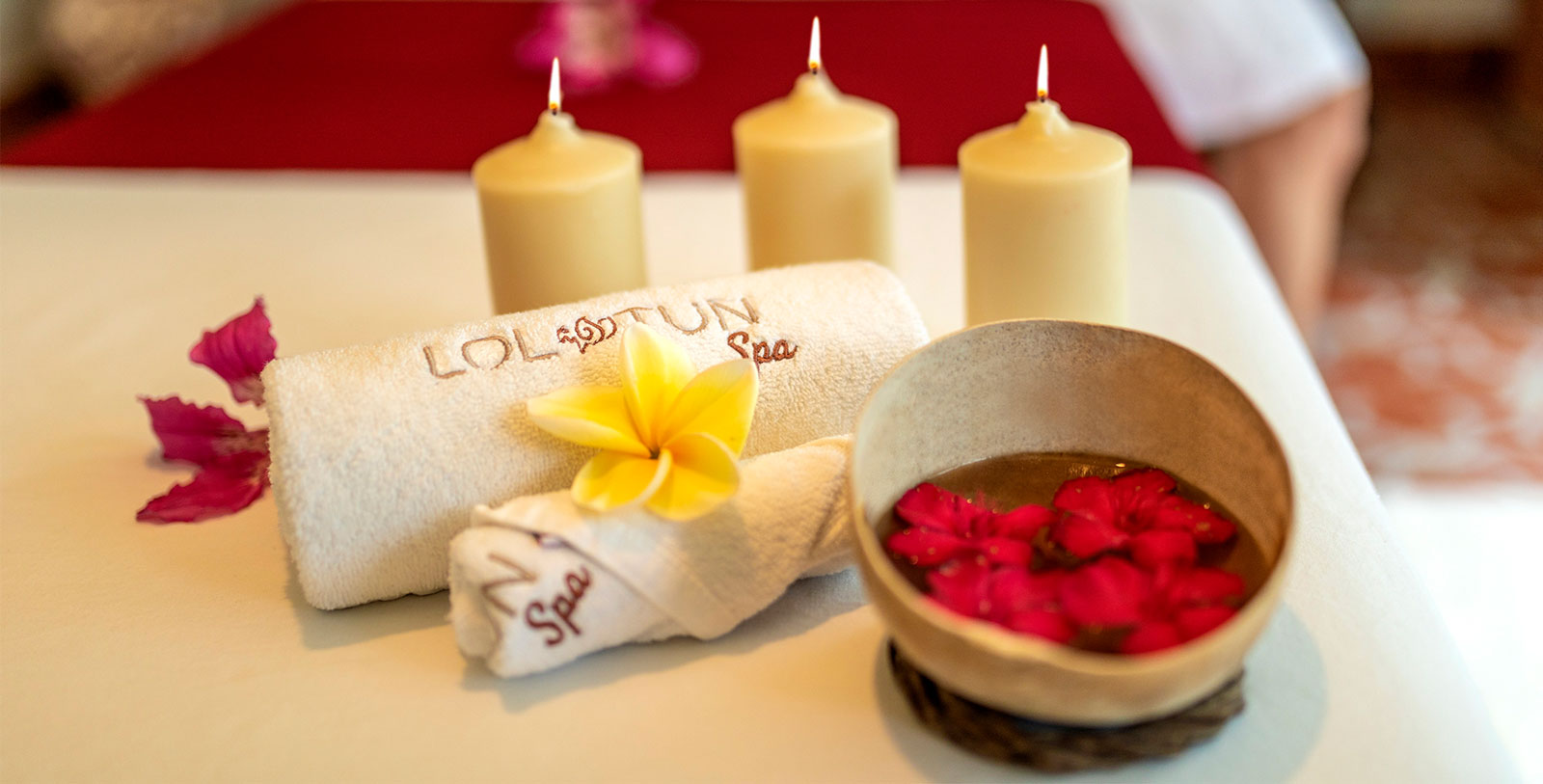 candles and towels with flowers in a bowl and a bowl of water
