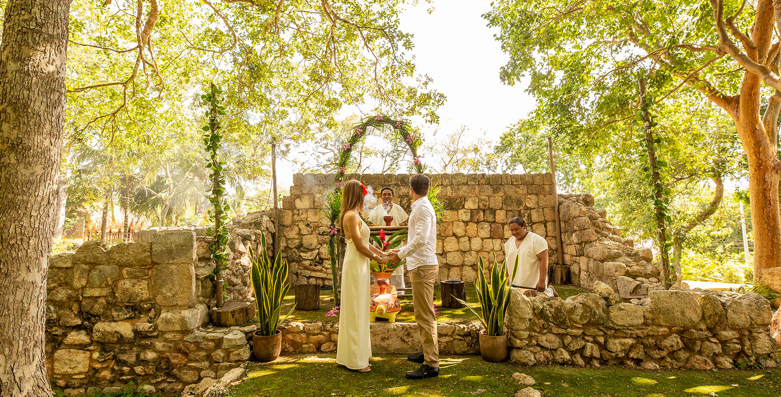 a man and woman holding hands under a stone arch