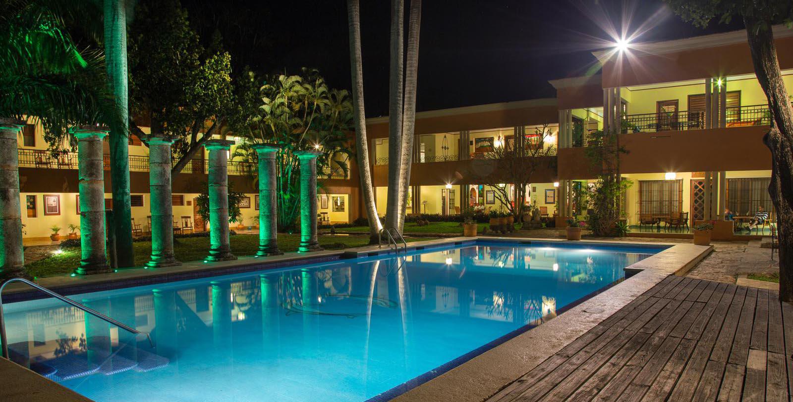 a pool with palm trees and a building at night