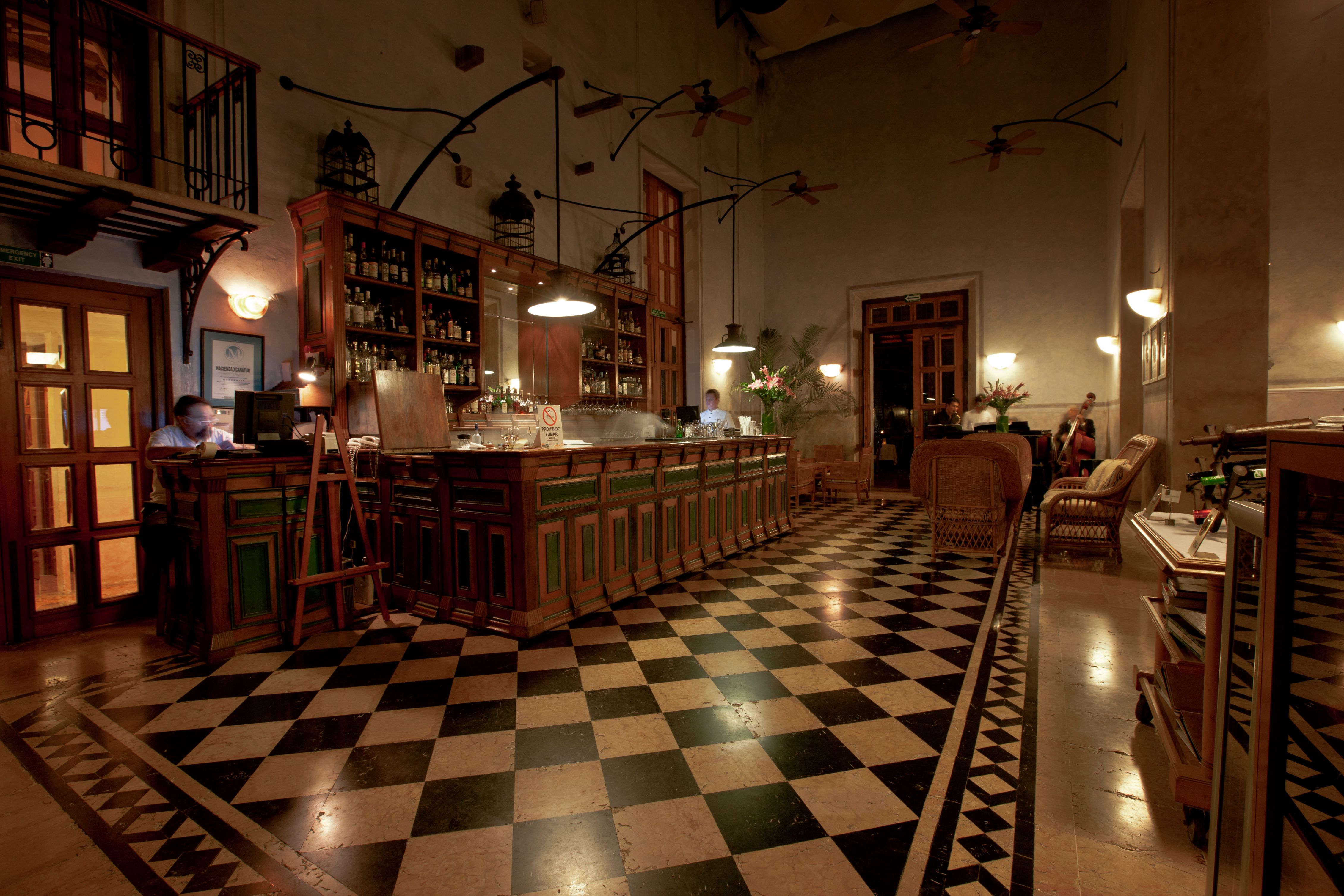 a bar with a checkered floor and a couple of people sitting in the back