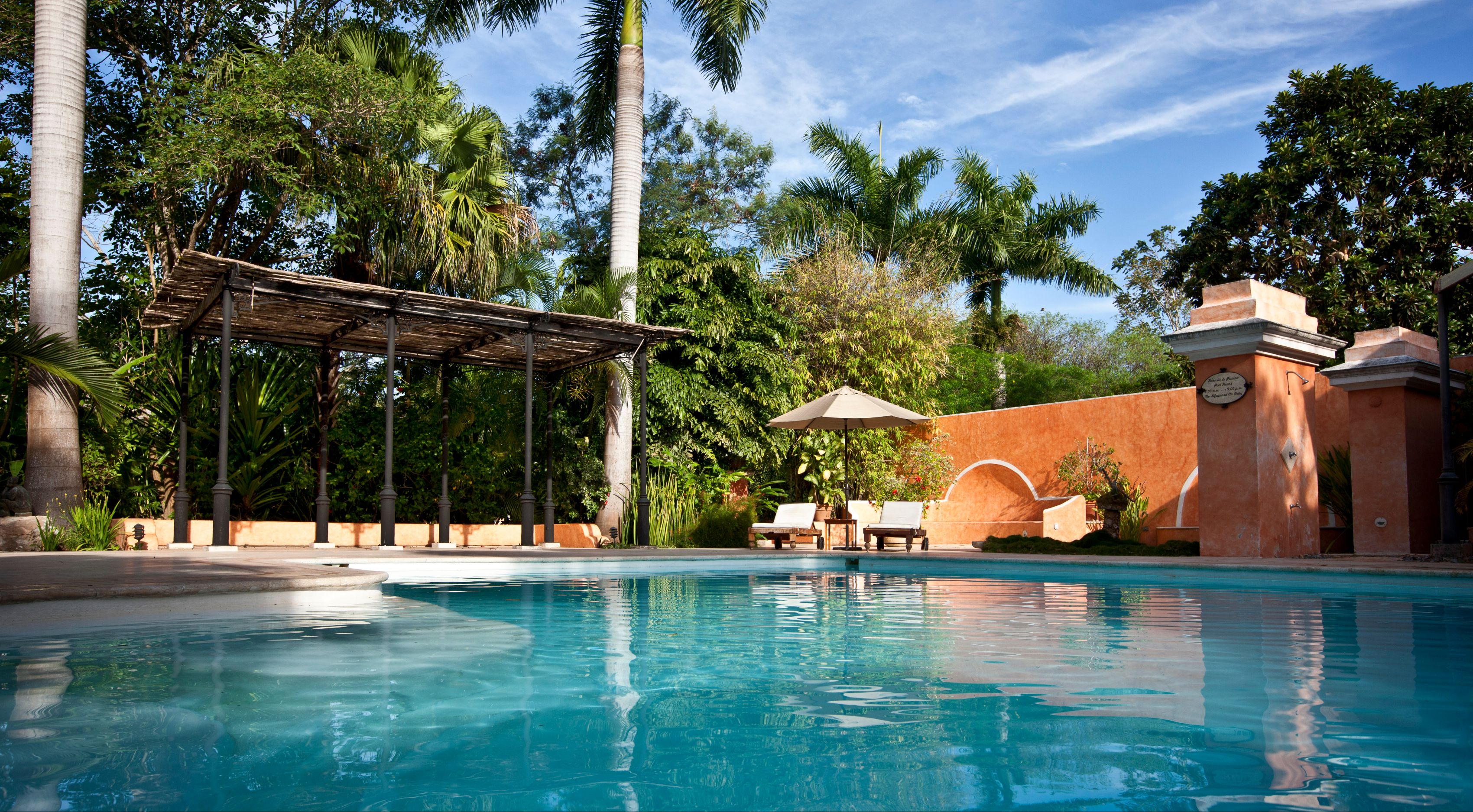 a pool with chairs and umbrellas in front of a building