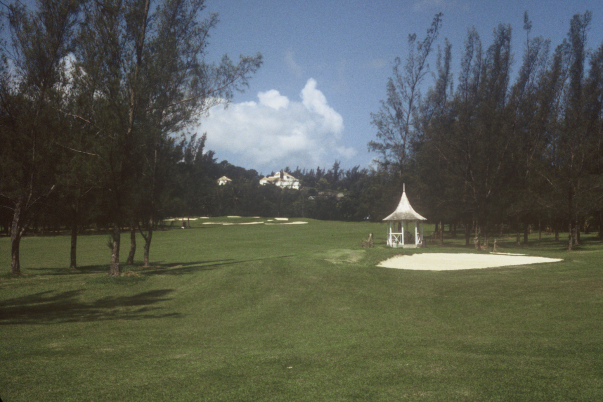 a golf course with a white gazebo and sand bunker