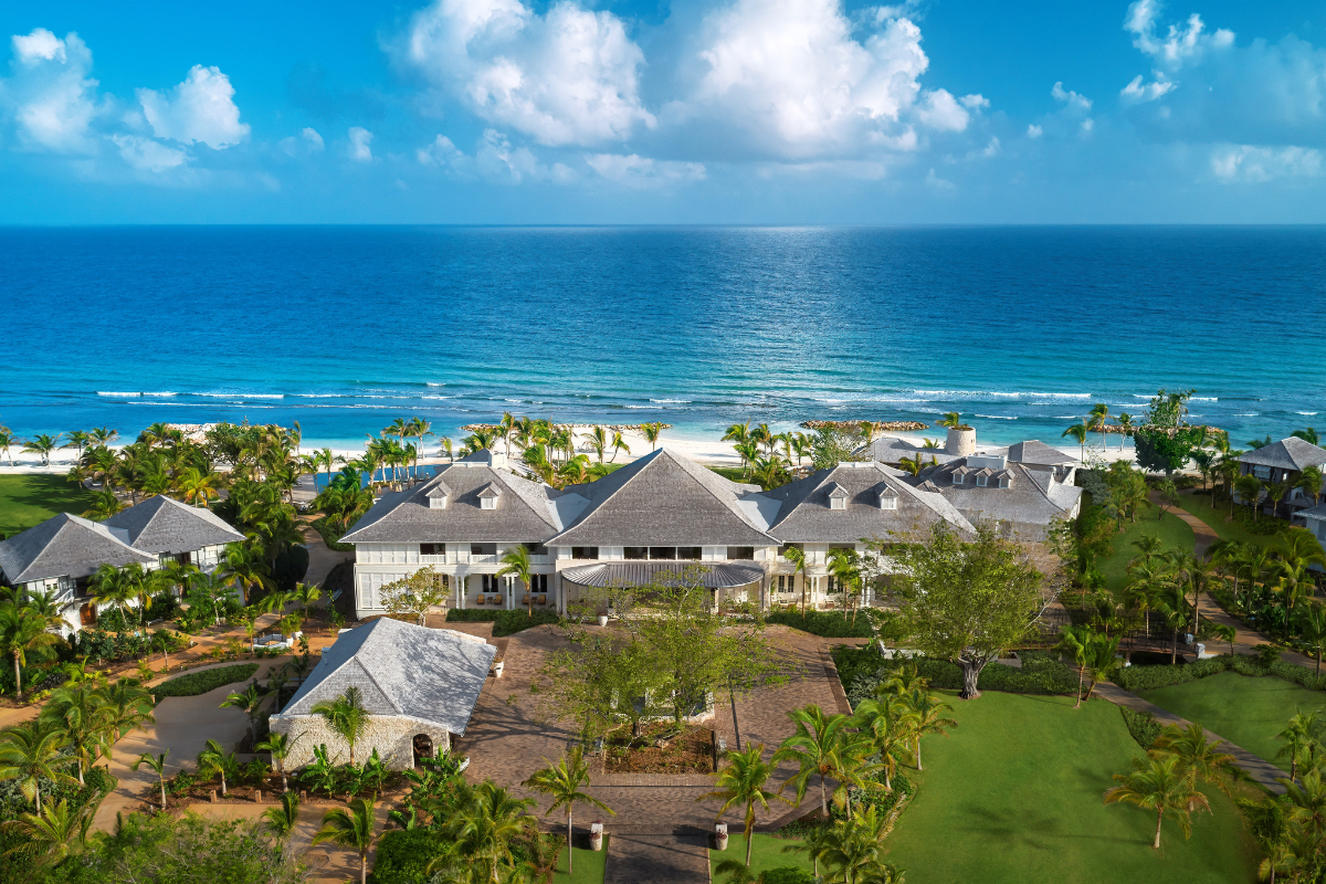 a large white house with trees and a beach in the background