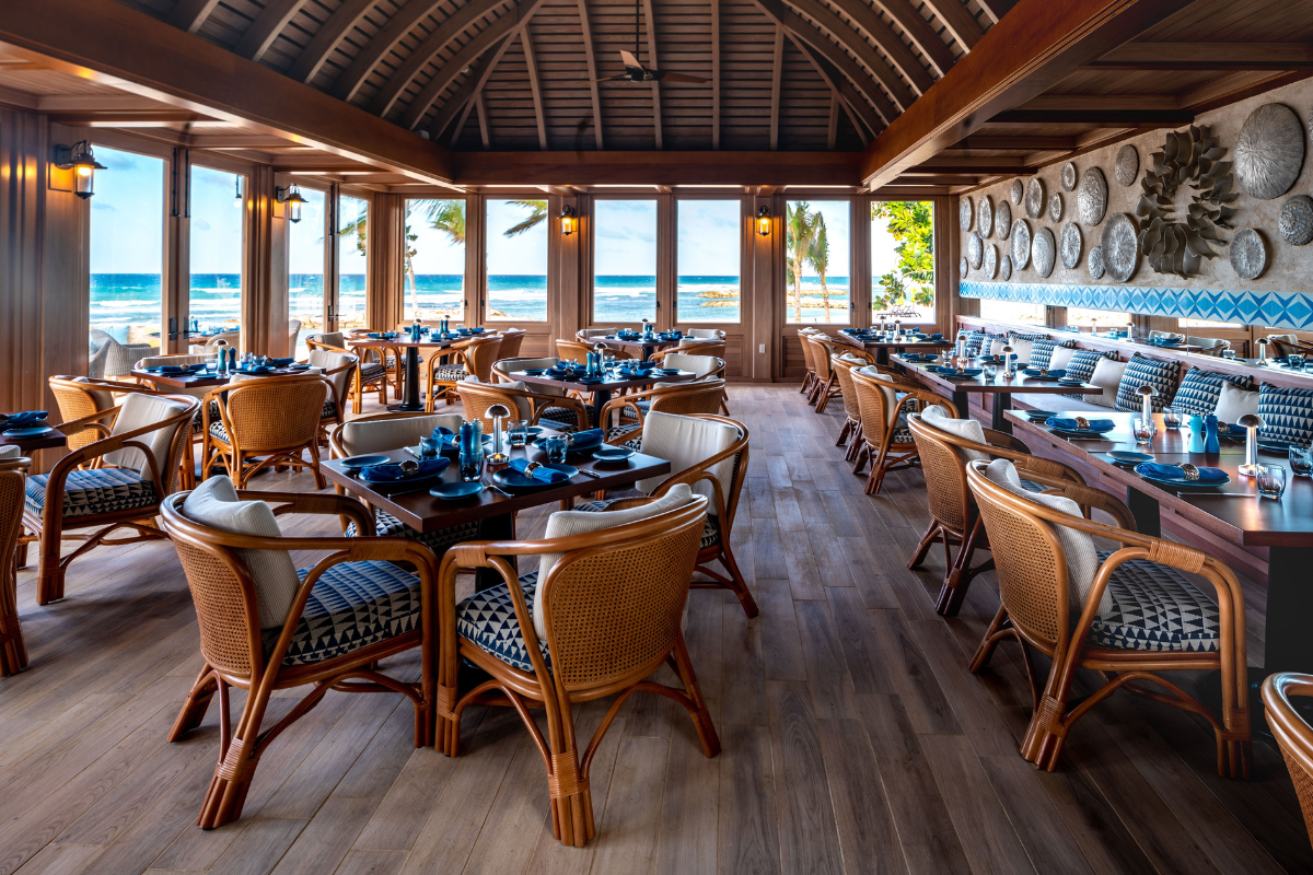 a room with tables and chairs and a view of the ocean