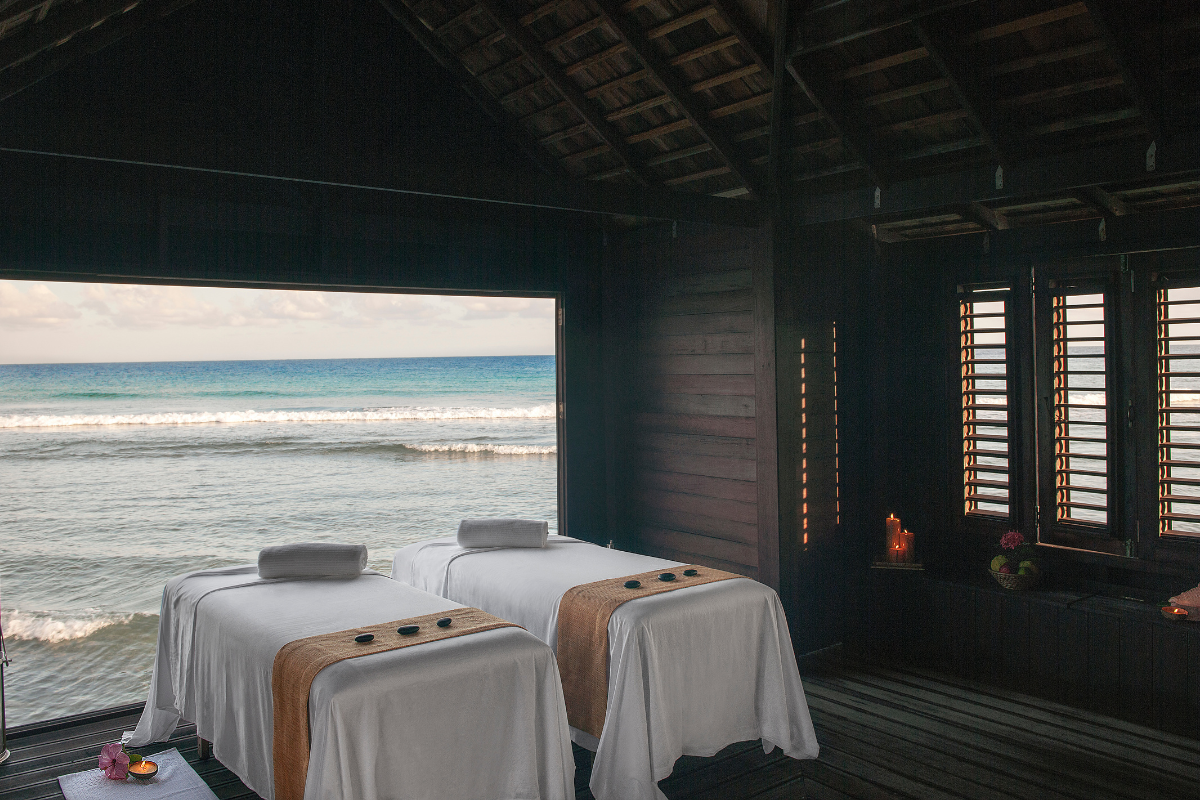 a room with two massage beds and a view of the ocean