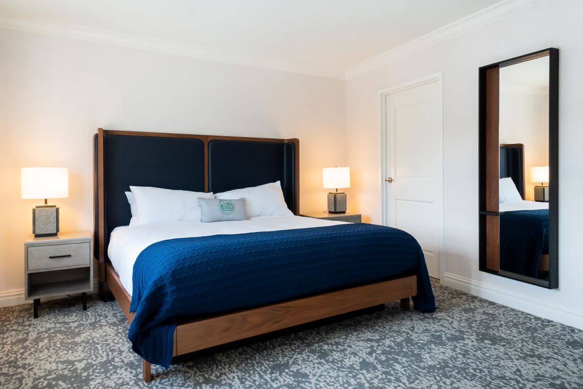 a bed with a blue blanket and a lamp in a room