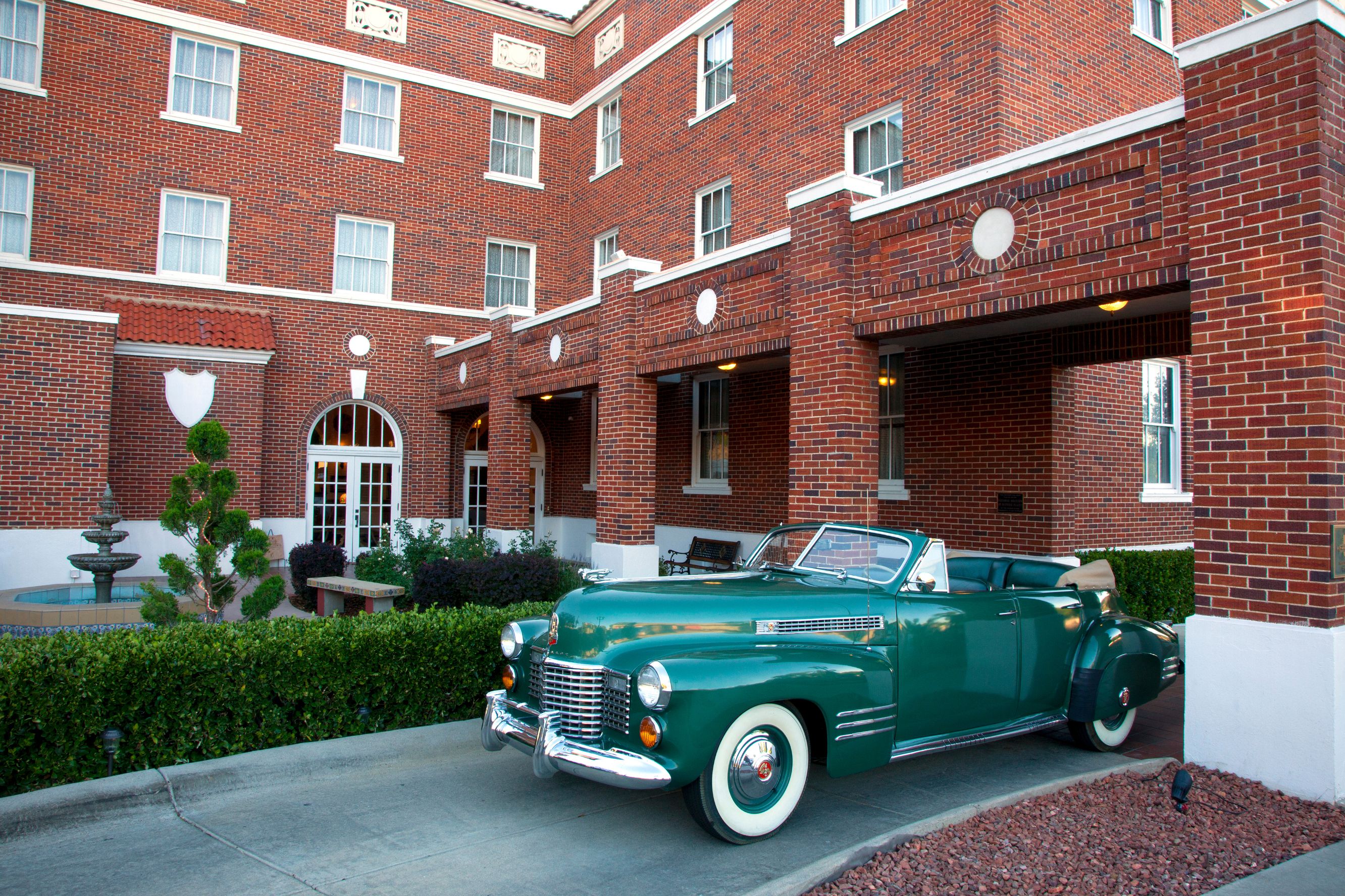 a green car parked in front of a brick building