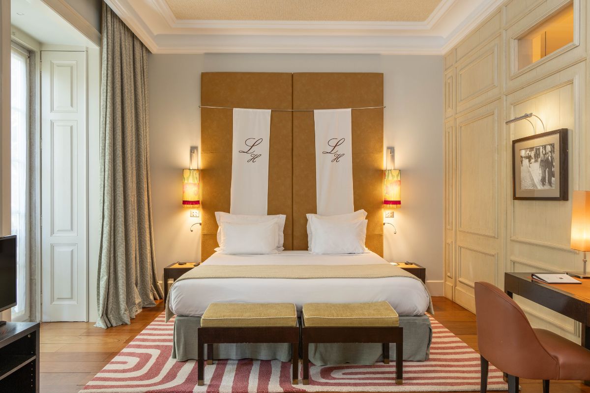 a bed with a headboard and stools in a room