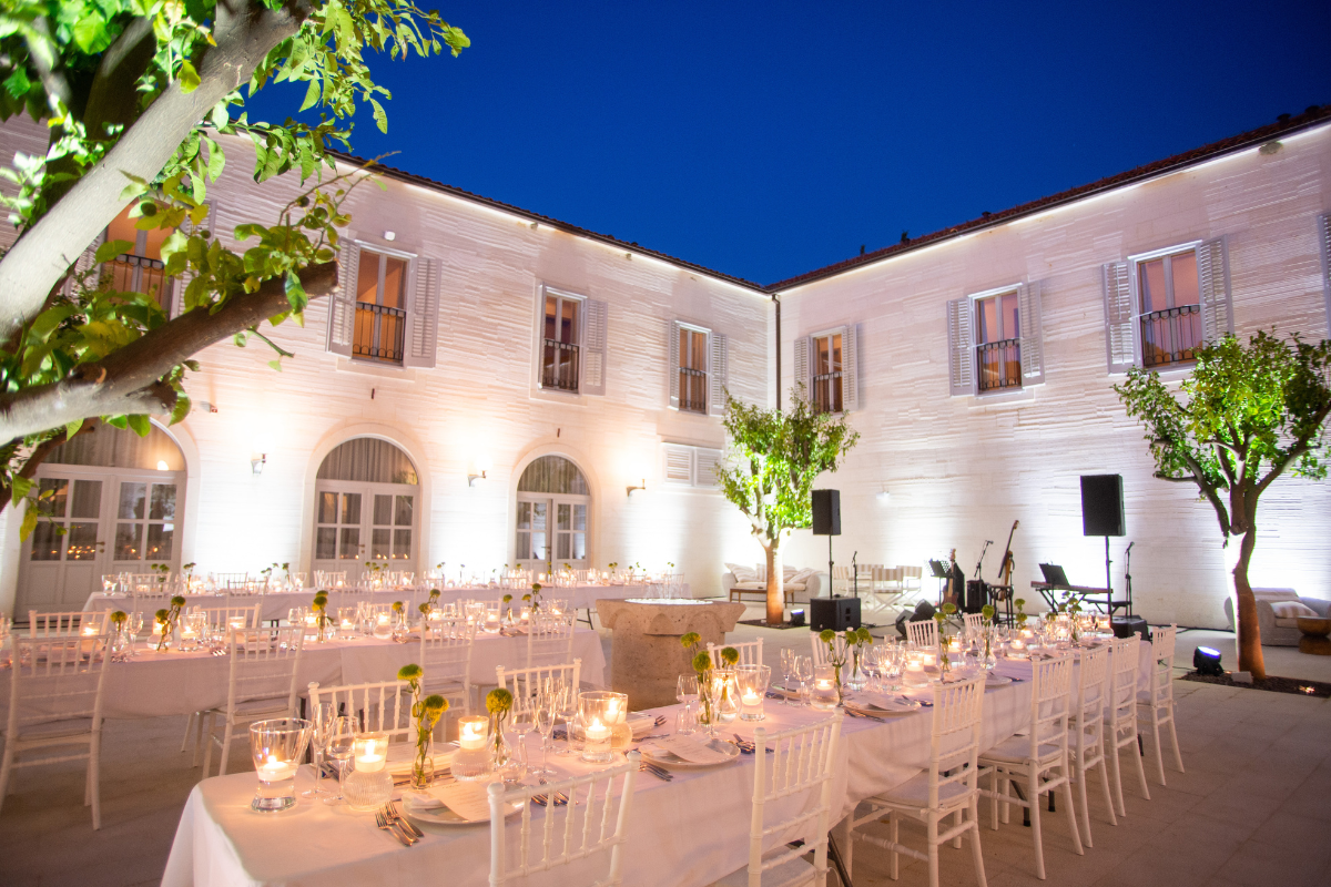 a white building with tables and chairs with candles