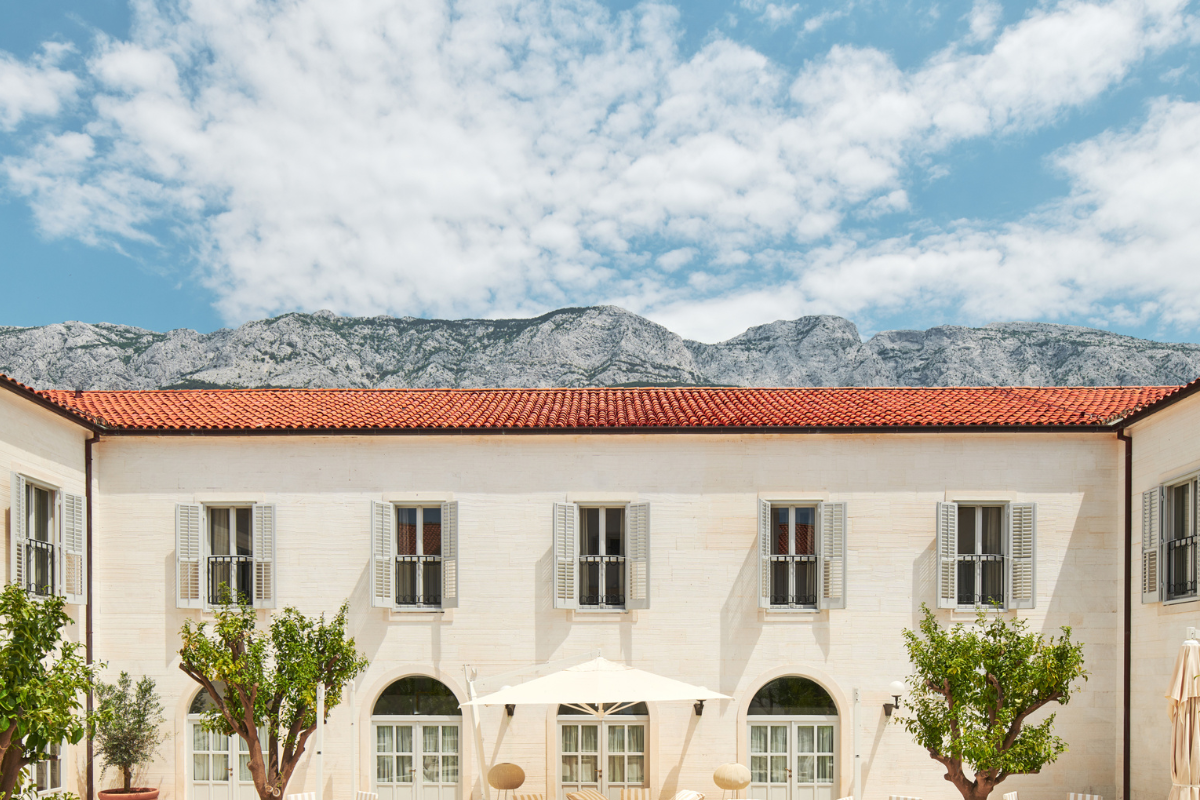 a building with trees and a mountain in the background