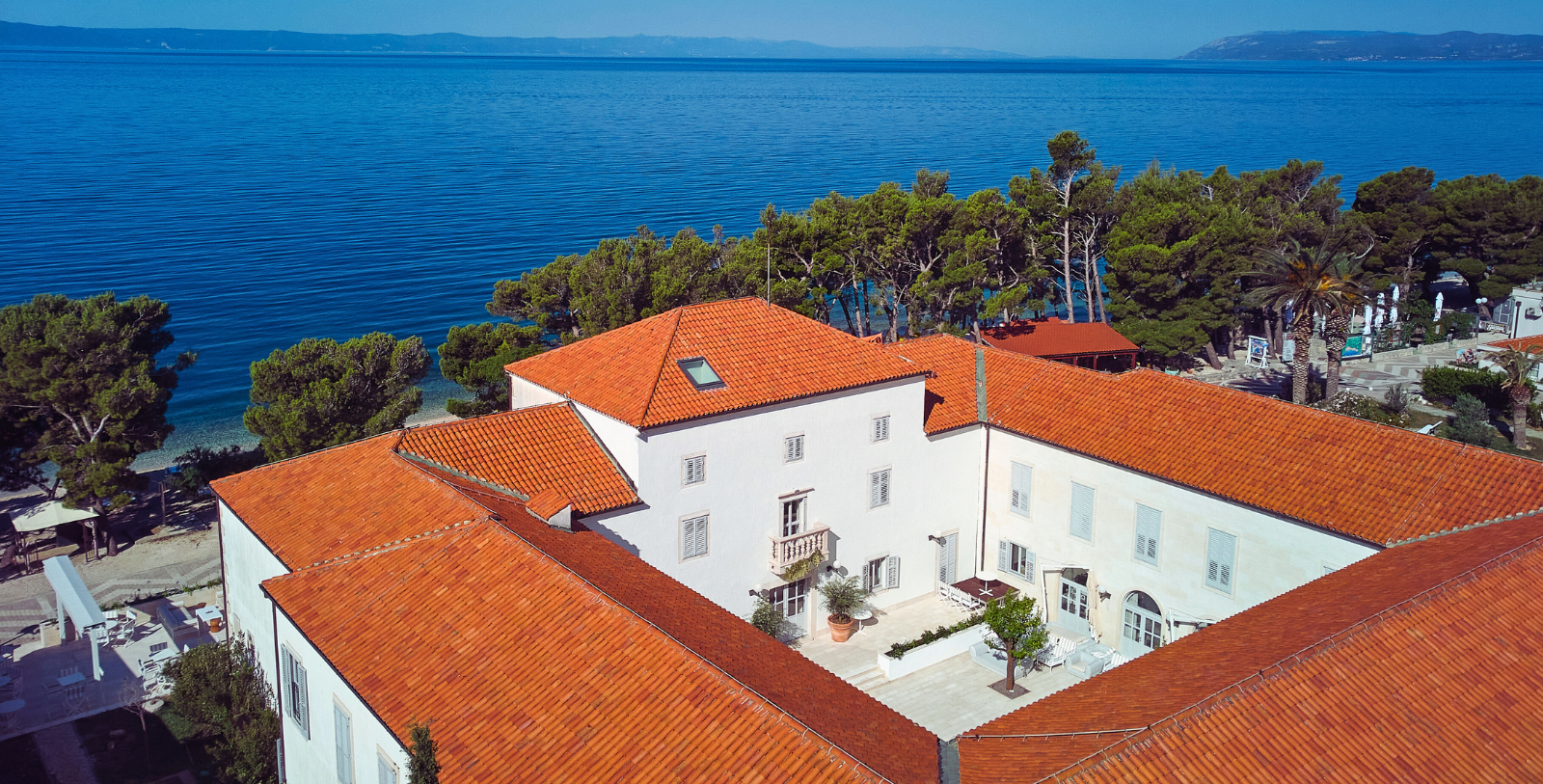 Casa Malaparte with red roofs and trees by the water