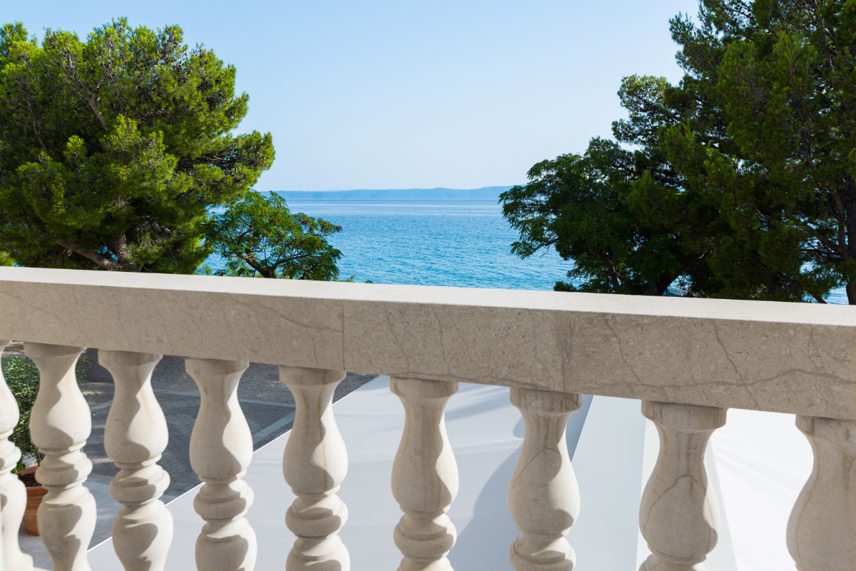 a white stone railing with trees and water in the background