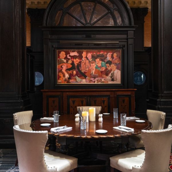 a table with white chairs and a painting on the wall