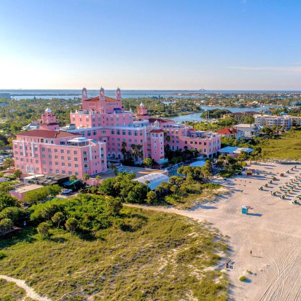 a large pink building with a beach and grass