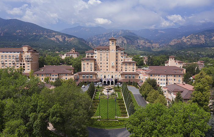 a large building with a lawn and trees in front of it