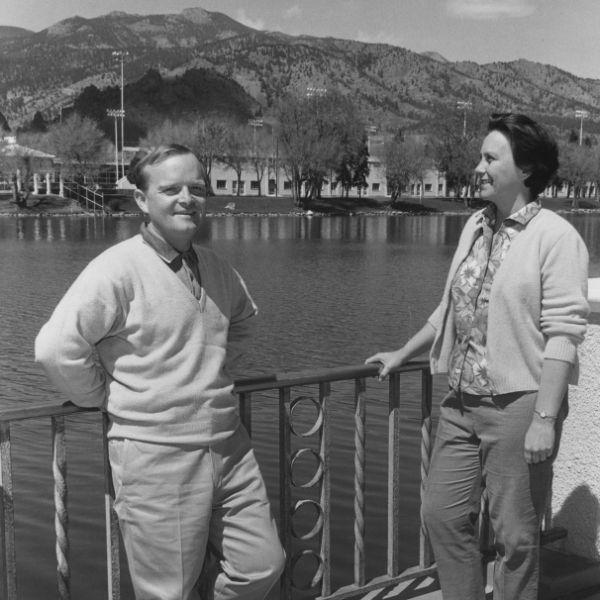 a man and woman standing next to a lake