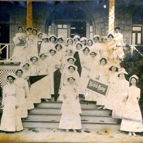 a group of women in white dresses posing for a photo