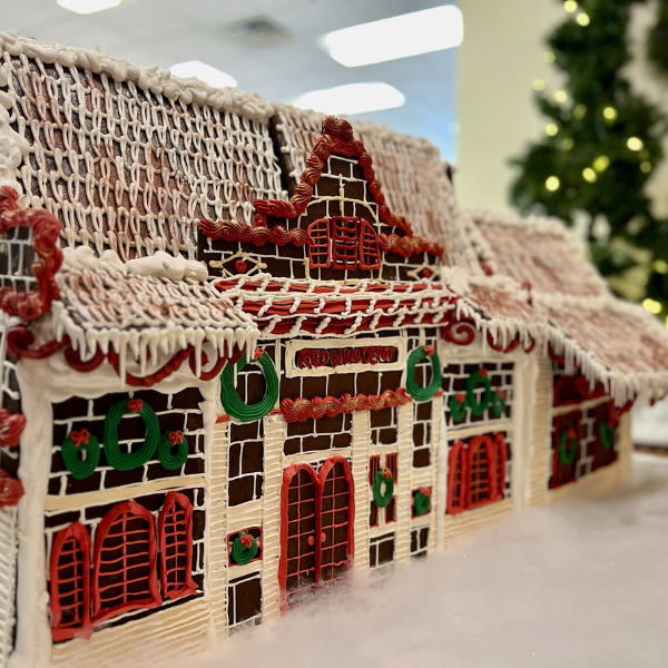 a gingerbread house with a christmas tree in the background