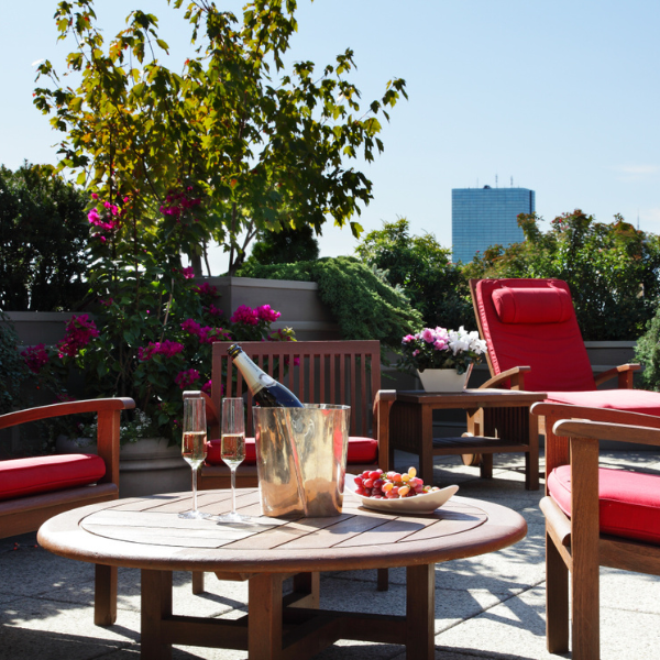 a table with wine glasses and a plate of food on it on a patio