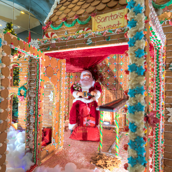 a gingerbread house with a santa claus sitting in it
