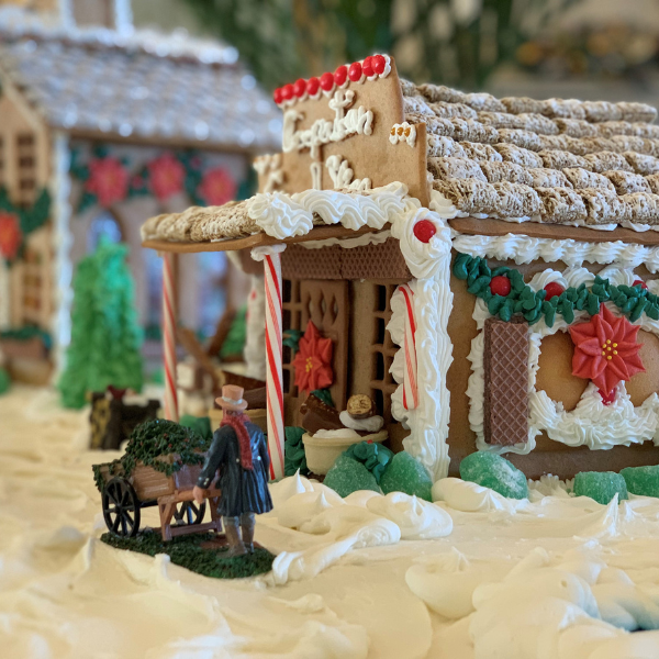 a gingerbread house with a man standing next to a cart