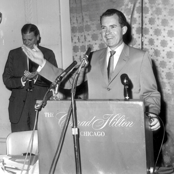 a man standing at a podium with microphones