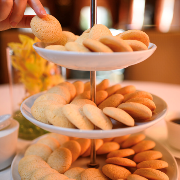 a hand reaching for a cookie on a tiered tray