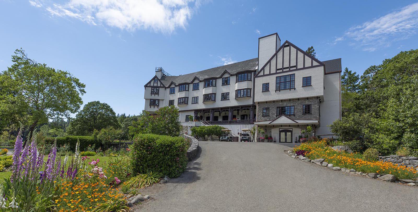 a large building with a driveway and flowers