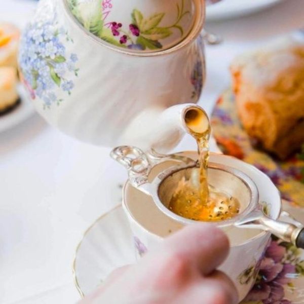 a person pouring tea into a cup