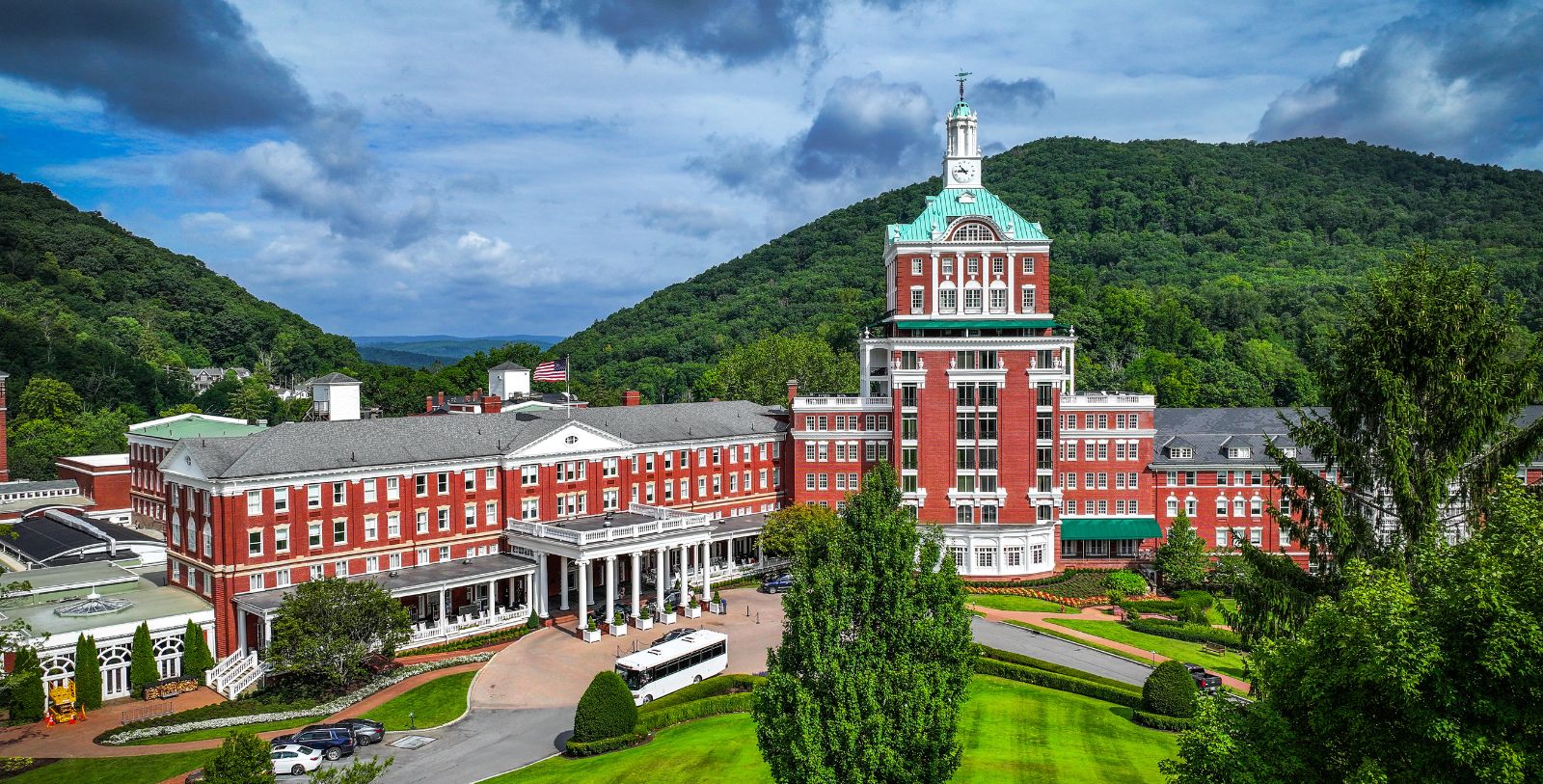 a large building with a clock tower and a green lawn with The Homestead in the background