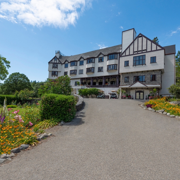 a large building with a driveway and flowers