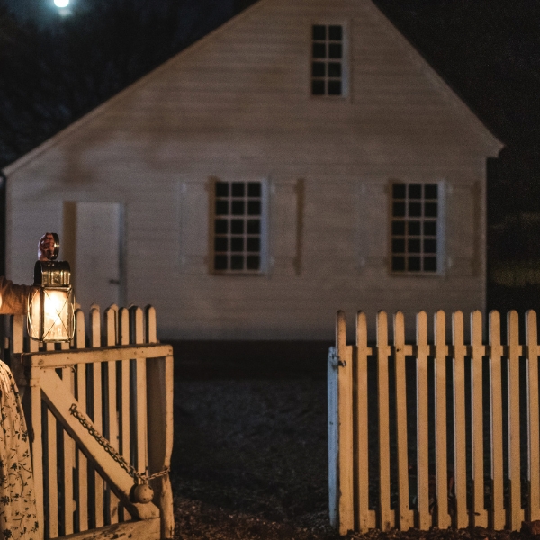 a person holding a lantern in front of a white fence