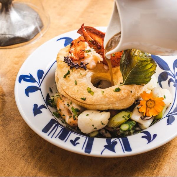 a bowl of food with a white pitcher pouring sauce