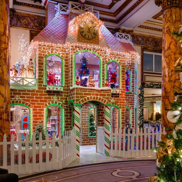 a gingerbread house with lights and a white fence