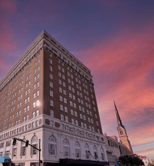 a building with a steeple and a pink sky