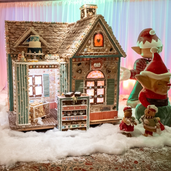 a gingerbread house with a couple of gnomes and a toy elf