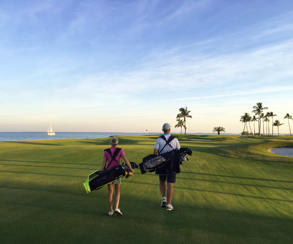 a man and woman walking on a golf course