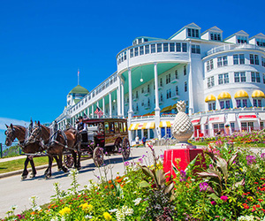 a horse drawn carriage in front of a large white building with Grand Hotel in the background