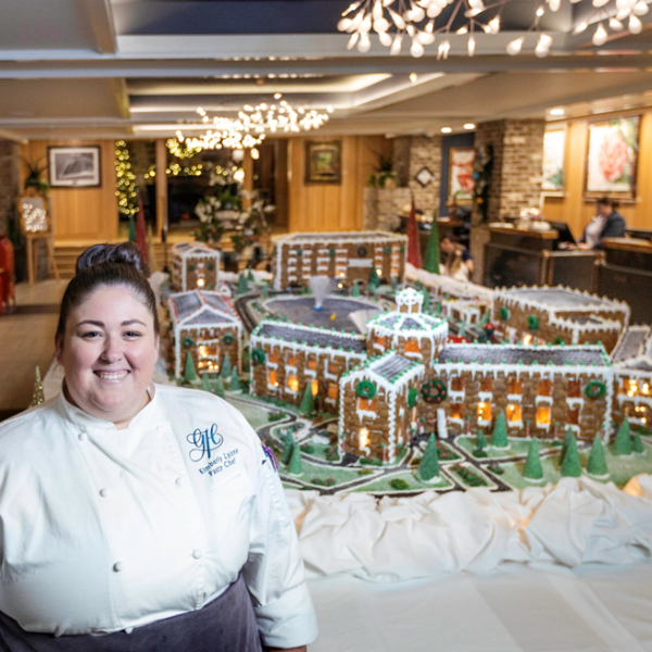 a woman standing in front of a gingerbread house
